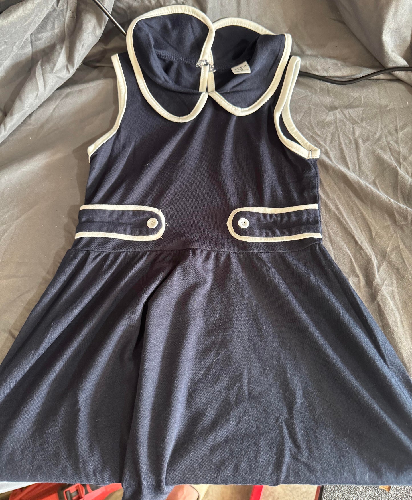 Navy blue dress with white trim on a gray surface