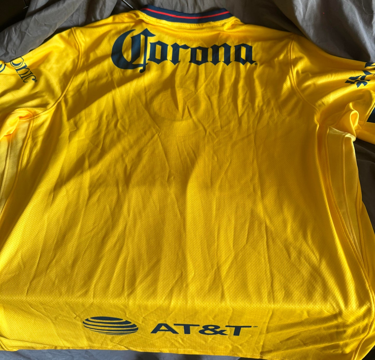 Yellow sports jersey with Corona and AT&T logos on a dark background