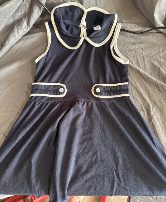 Navy blue dress with white trim on a gray surface
